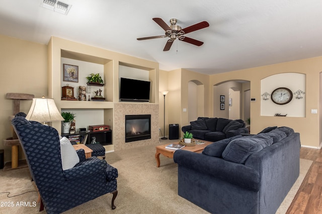 5735 S Cloverdale Ln, Gilbert, AZ 85298 - living room with a ceiling fan, arched walkways, a fireplace, built in shelves, and wood finished floors