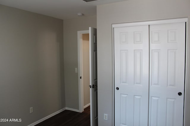 unfurnished bedroom with a closet and dark wood-type flooring