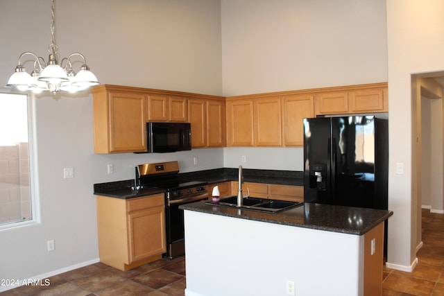 kitchen with sink, a high ceiling, a chandelier, a kitchen island with sink, and black appliances