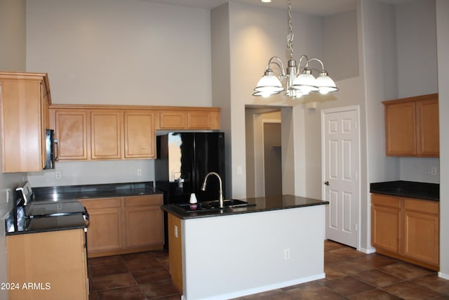 kitchen with a notable chandelier, a towering ceiling, a kitchen island with sink, and hanging light fixtures