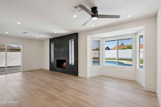 unfurnished living room featuring healthy amount of natural light, light wood-type flooring, recessed lighting, and baseboards