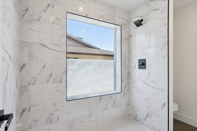 bathroom with a tile shower and toilet