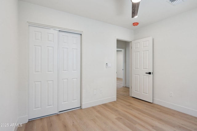 unfurnished bedroom featuring light wood-type flooring, baseboards, and a closet