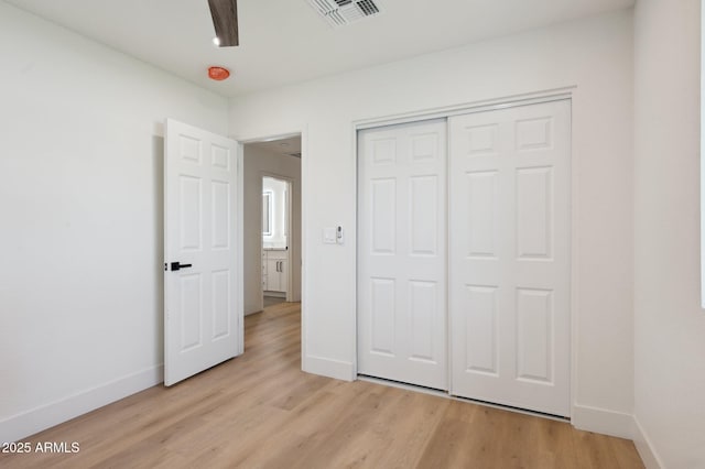 unfurnished bedroom with light wood-style floors, baseboards, and a closet