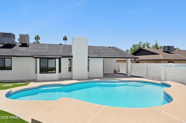 view of pool featuring a patio, fence, cooling unit, and a pool with connected hot tub