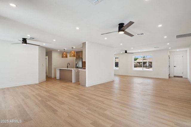 unfurnished living room with ceiling fan, recessed lighting, a sink, light wood finished floors, and baseboards