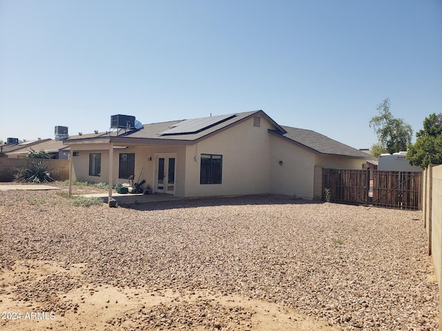 back of house featuring cooling unit, solar panels, and a patio area