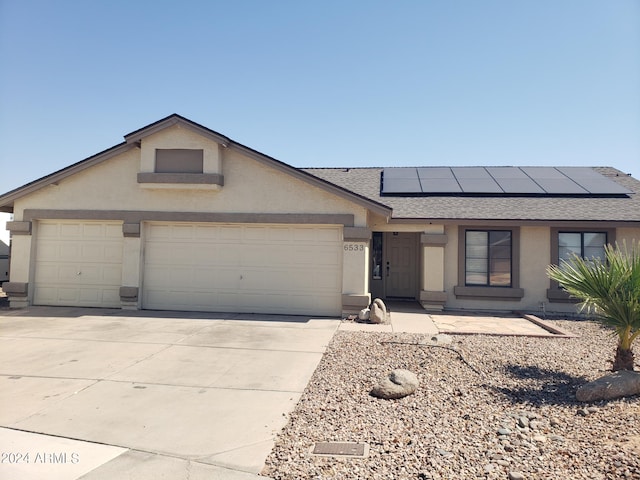 ranch-style home with solar panels and a garage