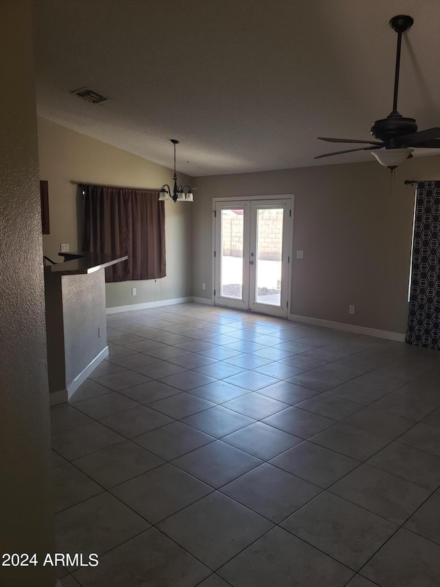 tiled empty room with ceiling fan with notable chandelier and lofted ceiling