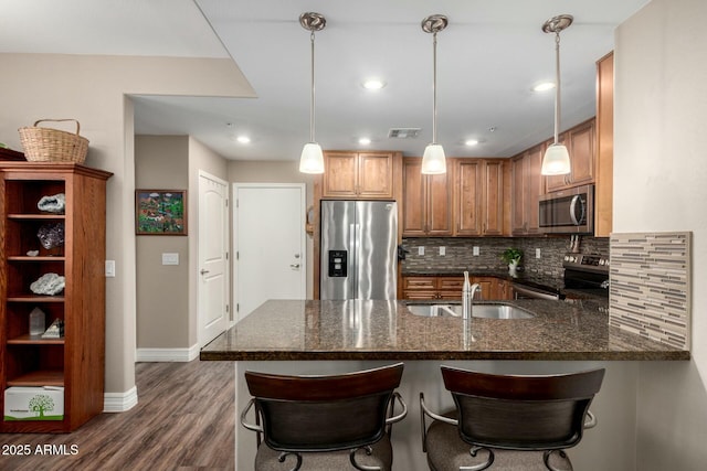 kitchen featuring visible vents, decorative backsplash, dark stone counters, appliances with stainless steel finishes, and a peninsula