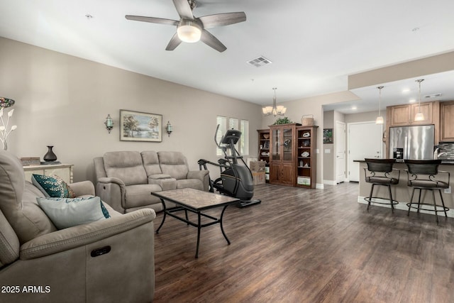 living room featuring dark wood-type flooring, visible vents, baseboards, and a ceiling fan