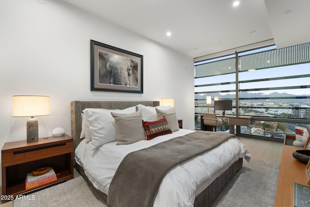 bedroom with floor to ceiling windows and light hardwood / wood-style flooring