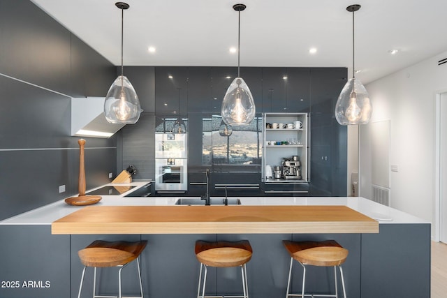 kitchen featuring a kitchen breakfast bar, sink, oven, and hanging light fixtures