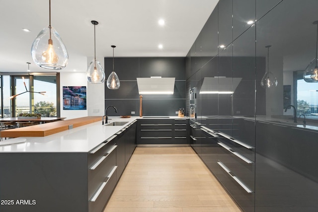 kitchen with light hardwood / wood-style floors, sink, and hanging light fixtures