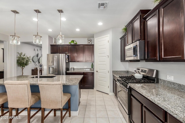 10454 W Maya Way, Peoria, AZ 85383 - kitchen featuring light stone counters, a sink, a breakfast bar, stainless steel appliances, and visible vents
