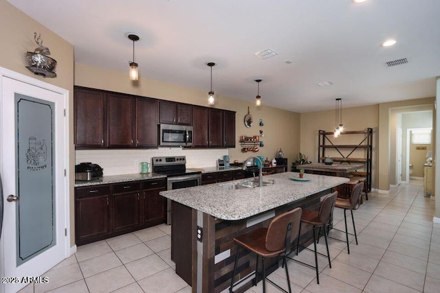 18309 N Crestview Ln, Maricopa, AZ 85138 - kitchen featuring appliances with stainless steel finishes, a sink, light tile patterned floors, a breakfast bar, and tasteful backsplash