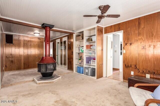 315 N 4th St, Tombstone, AZ 85638 - carpeted living room with wooden walls, a wood stove, a ceiling fan, and ornamental molding