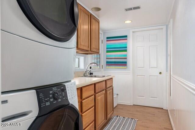 315 N 4th St, Tombstone, AZ 85638 - laundry room featuring a sink, visible vents, stacked washer / drying machine, light wood finished floors, and cabinet space