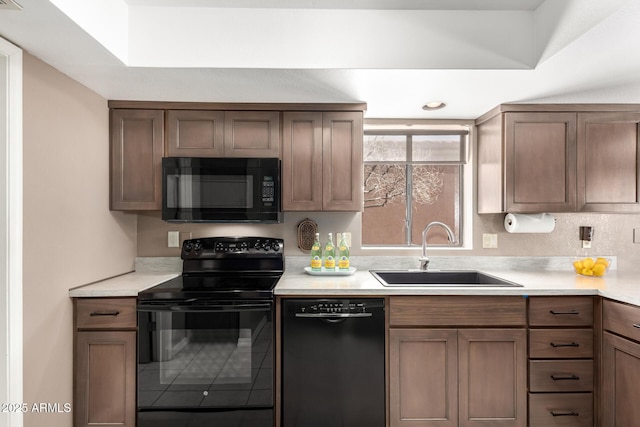 kitchen featuring black appliances, light countertops, and a sink