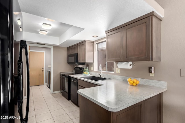 kitchen featuring light countertops, a sink, black appliances, and dark brown cabinets