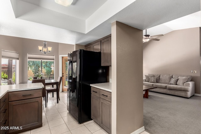 kitchen with light countertops, dark brown cabinets, freestanding refrigerator, and decorative light fixtures