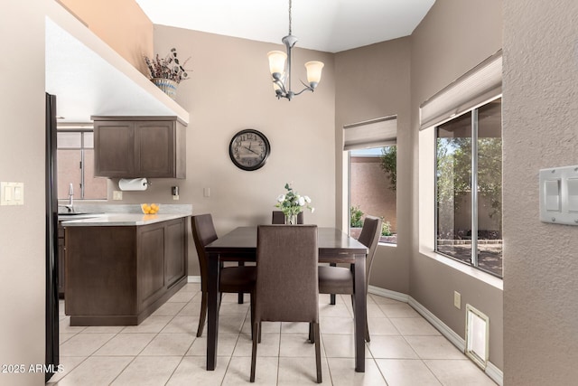 dining space featuring baseboards, light tile patterned flooring, a towering ceiling, and an inviting chandelier