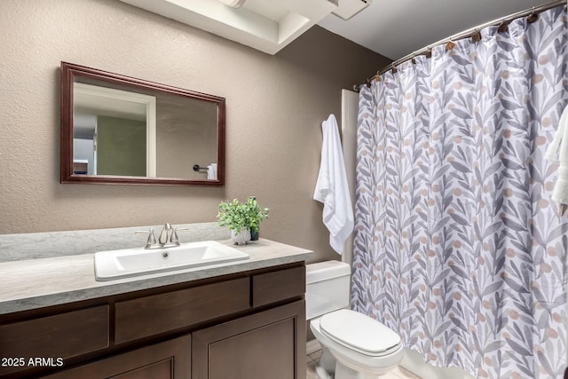 full bath with a textured wall, vanity, and toilet