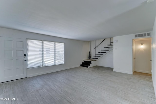 interior space with wood finished floors, visible vents, baseboards, and stairs