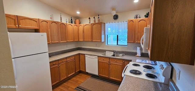 kitchen featuring white appliances, light hardwood / wood-style floors, vaulted ceiling, and sink