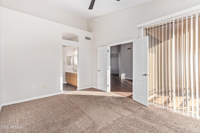 unfurnished bedroom with carpet, connected bathroom, a closet, vaulted ceiling, and ceiling fan