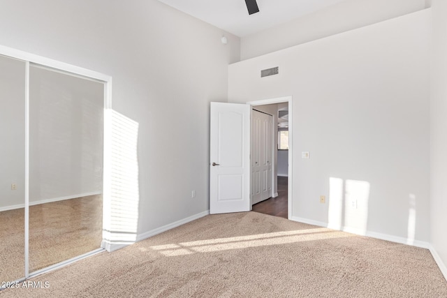 unfurnished bedroom with ceiling fan, a high ceiling, and carpet floors