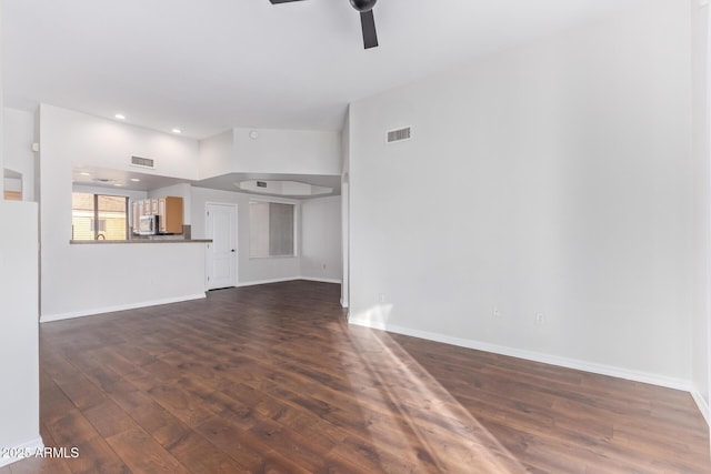 unfurnished living room with ceiling fan, a high ceiling, and dark hardwood / wood-style floors