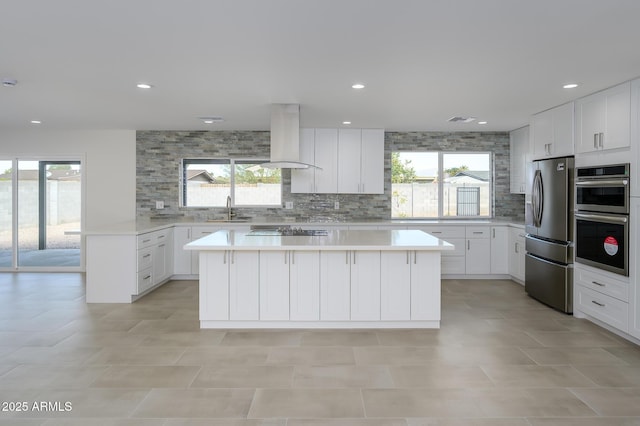 kitchen with appliances with stainless steel finishes, island range hood, a center island, and sink