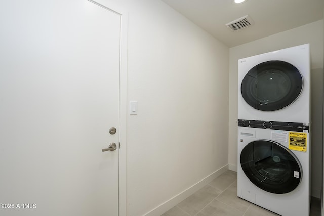 washroom featuring stacked washer and dryer and light tile patterned floors