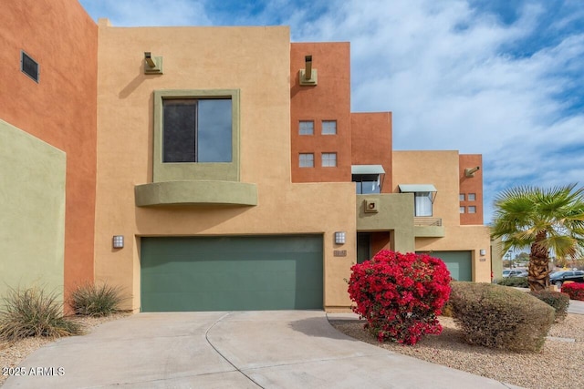 adobe home featuring an attached garage, concrete driveway, and stucco siding