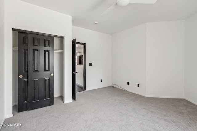 unfurnished bedroom featuring light colored carpet, baseboards, a closet, and a ceiling fan