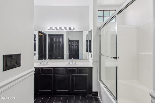 bathroom with enclosed tub / shower combo, double vanity, and wood finished floors