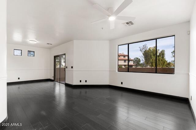 empty room featuring ceiling fan, dark wood-type flooring, and plenty of natural light