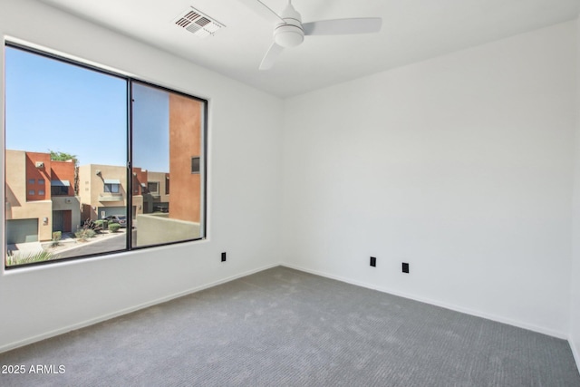 carpeted empty room with a ceiling fan and baseboards