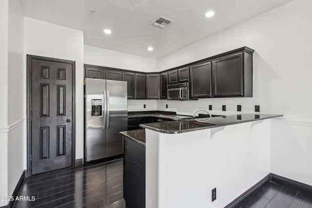 kitchen featuring stainless steel appliances, a peninsula, dark stone countertops, baseboards, and recessed lighting