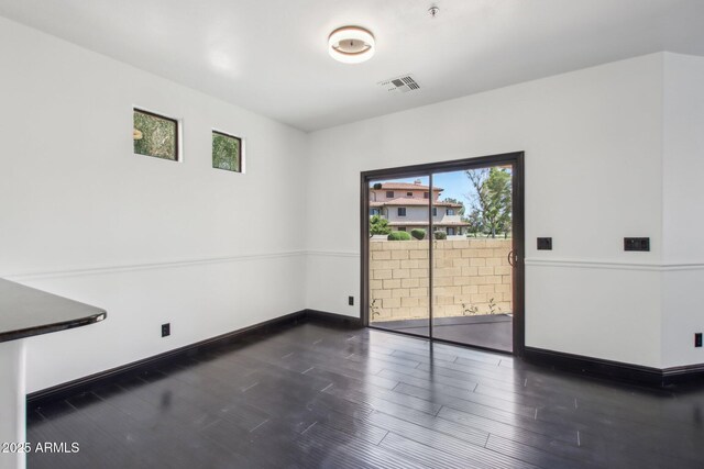 unfurnished dining area with dark wood-type flooring and baseboards