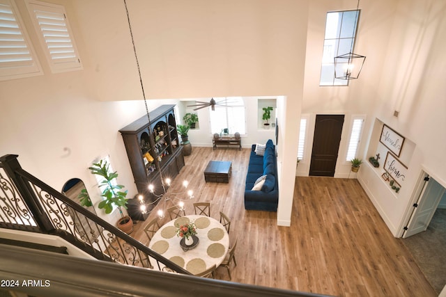 living room with ceiling fan with notable chandelier, a towering ceiling, and hardwood / wood-style flooring