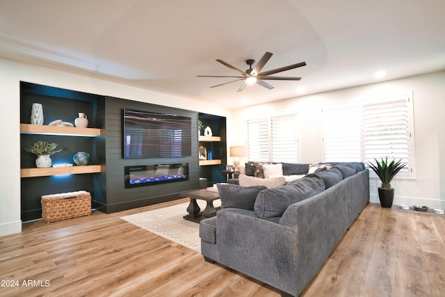 living room with a wealth of natural light, built in features, ceiling fan, and wood-type flooring