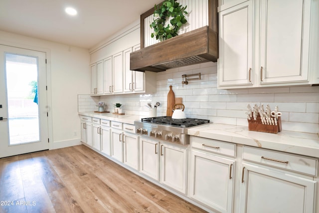 kitchen featuring tasteful backsplash, light stone counters, white cabinets, and stainless steel gas cooktop