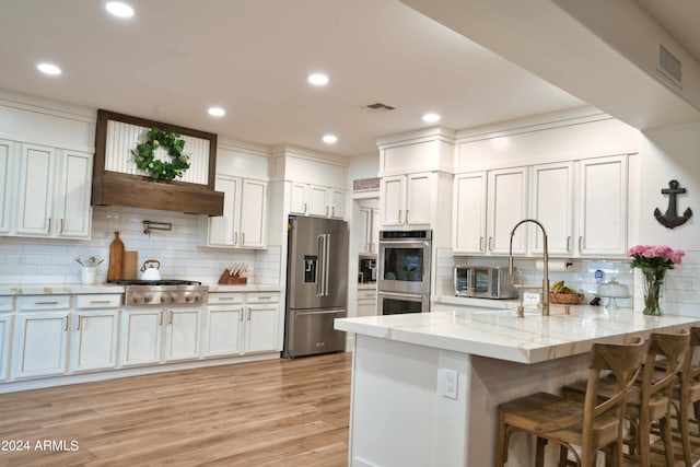 kitchen featuring decorative backsplash, white cabinetry, kitchen peninsula, and appliances with stainless steel finishes