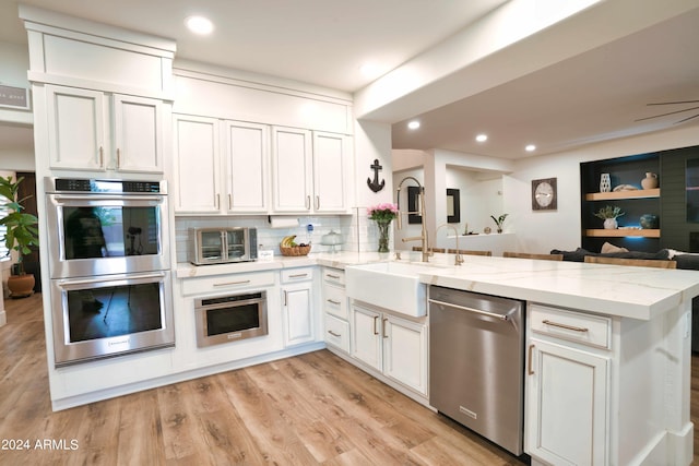 kitchen with white cabinets, light stone counters, kitchen peninsula, and stainless steel appliances