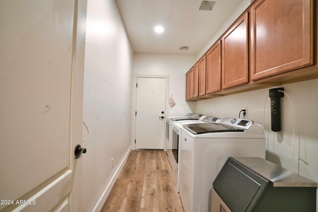 washroom featuring washer and dryer, light wood-type flooring, and cabinets