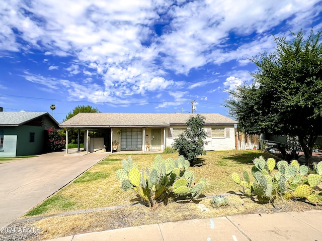 ranch-style home with an attached carport, fence, and driveway