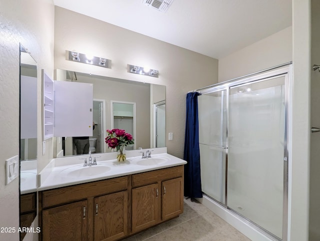 bathroom with vanity, toilet, tile patterned flooring, and a shower with door