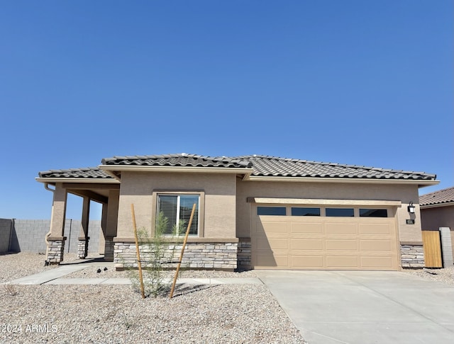 prairie-style home featuring stone siding, an attached garage, a tile roof, and stucco siding